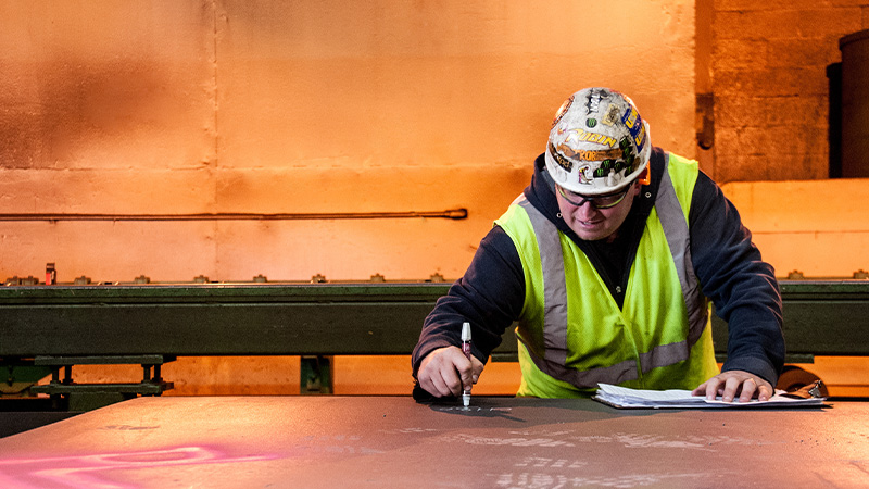 Worker inspecting large forged pipe products