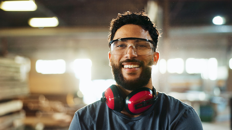 Smiling employee wearing safety glasses and ear protection